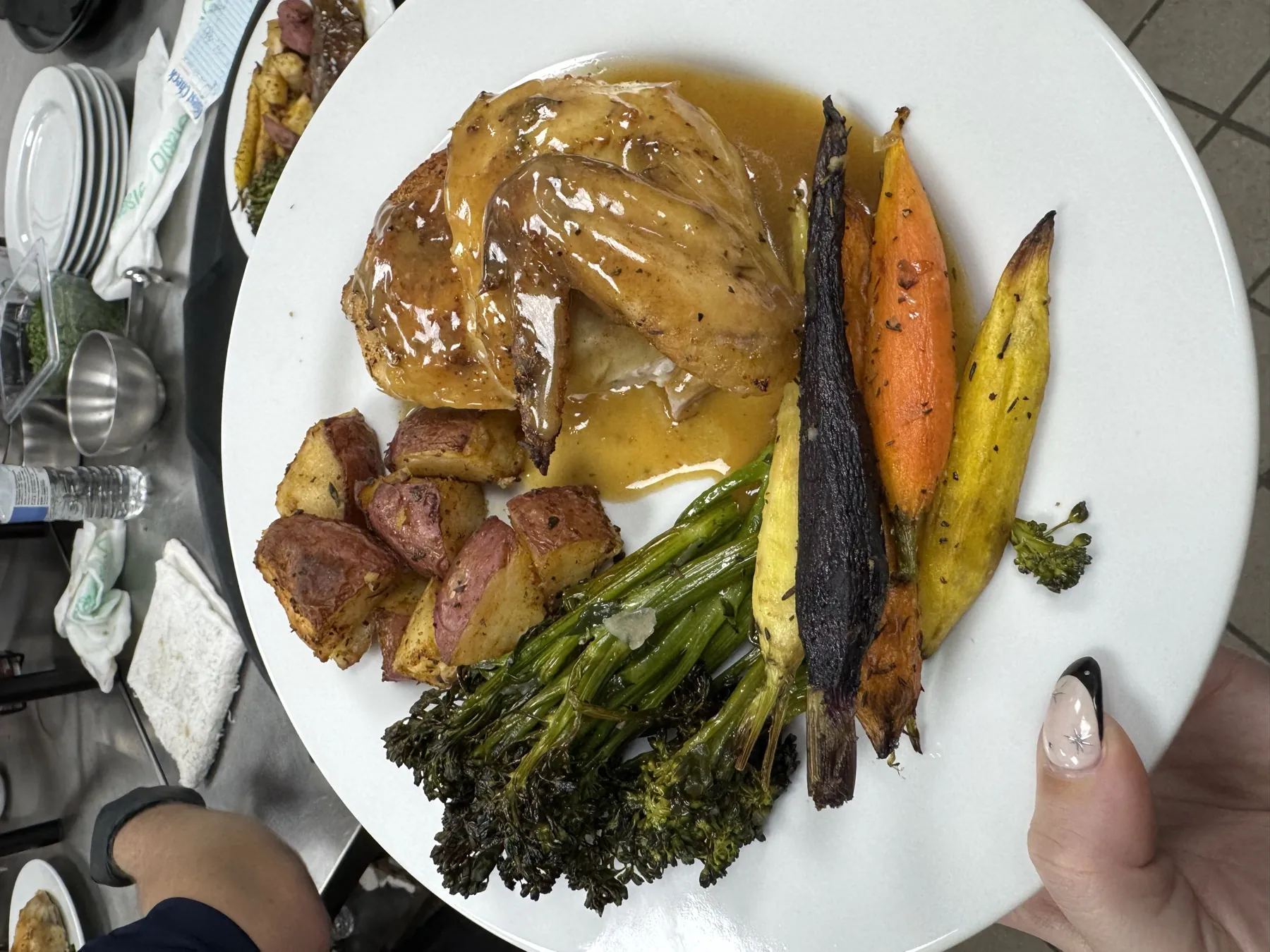 Plated chicken with roasted potatoes and seasonal vegetables