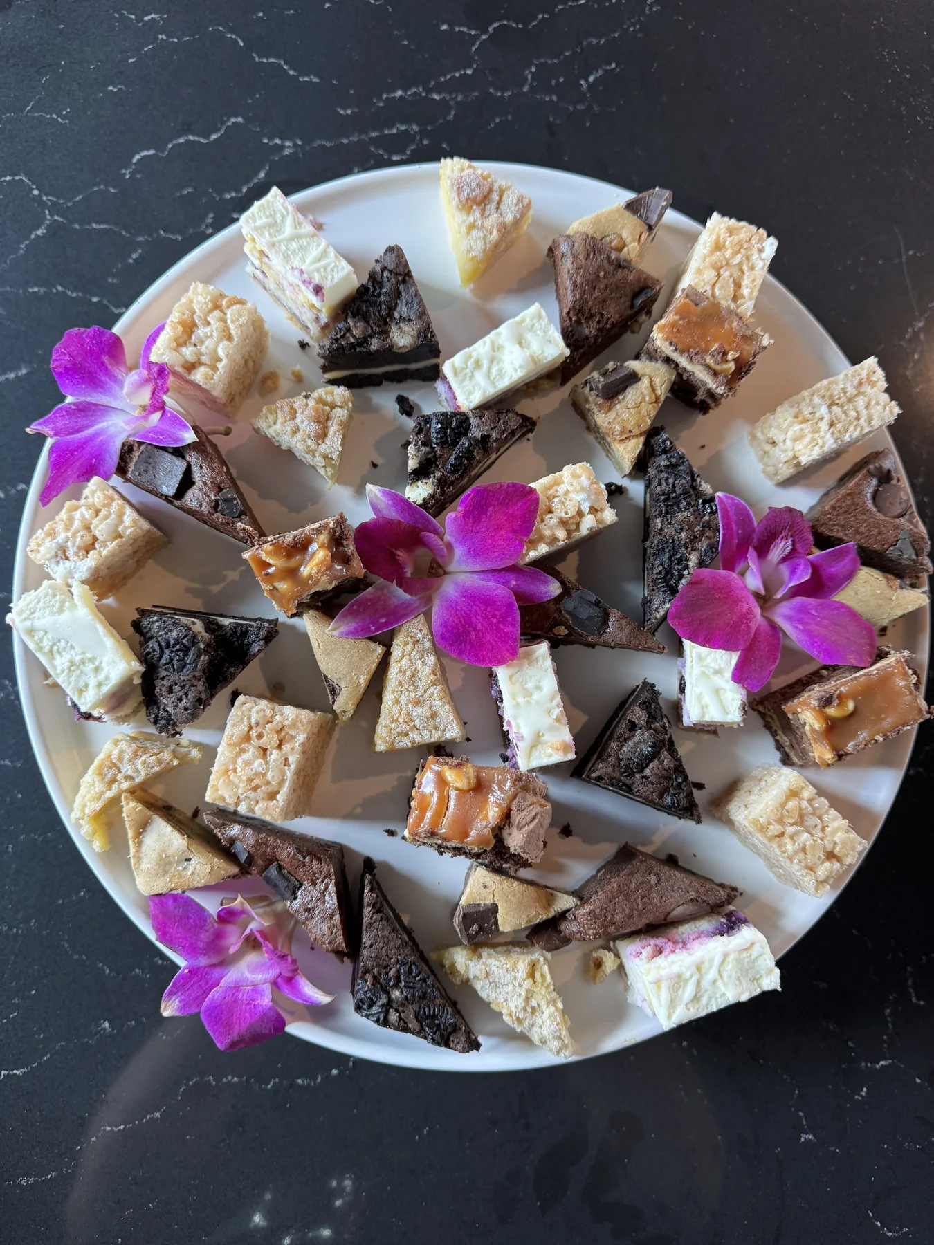 Assorted brownies and dessert bars arranged with edible flowers