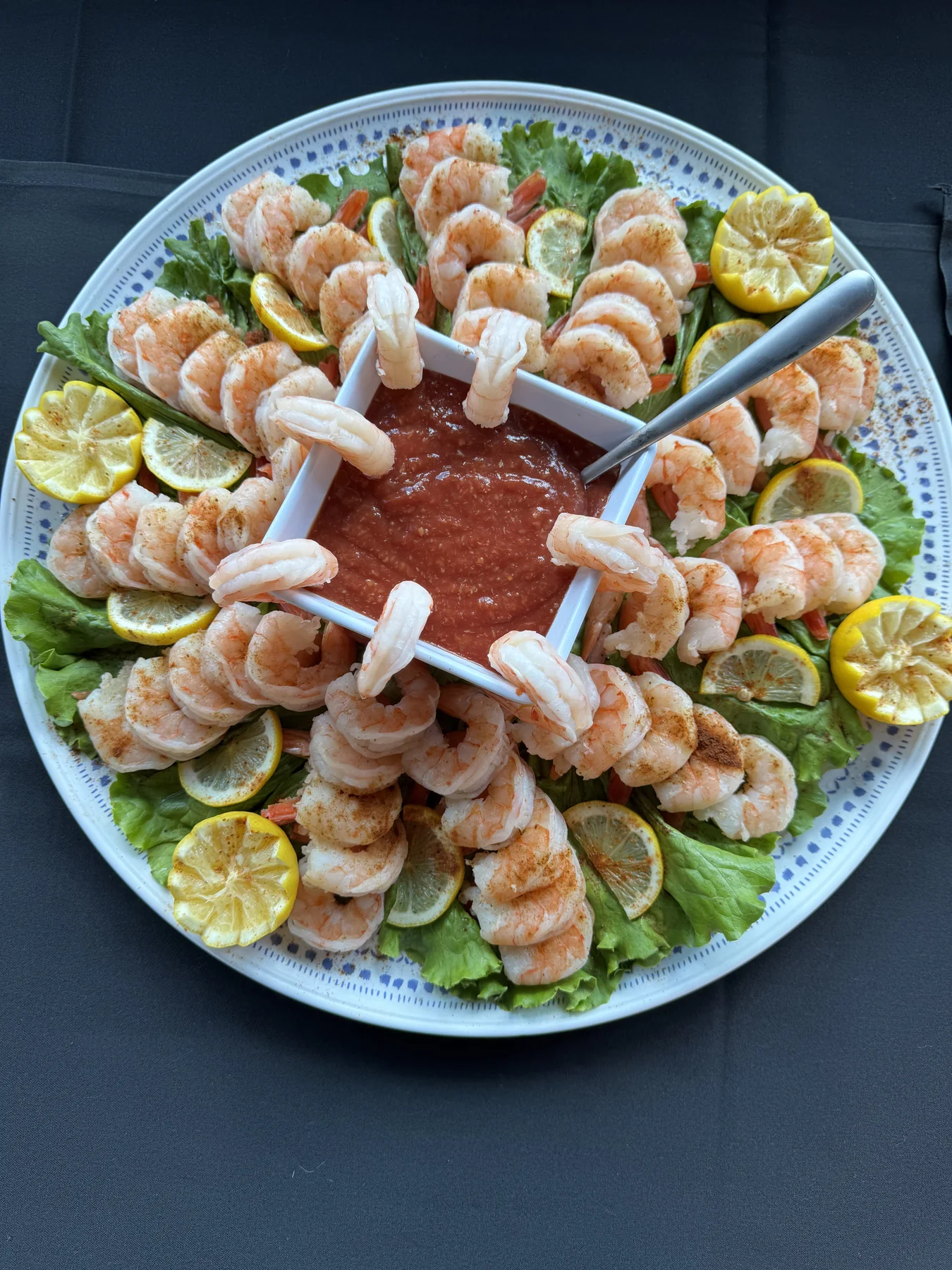 Shrimp cocktail platter with citrus, greens and cocktail sauce
