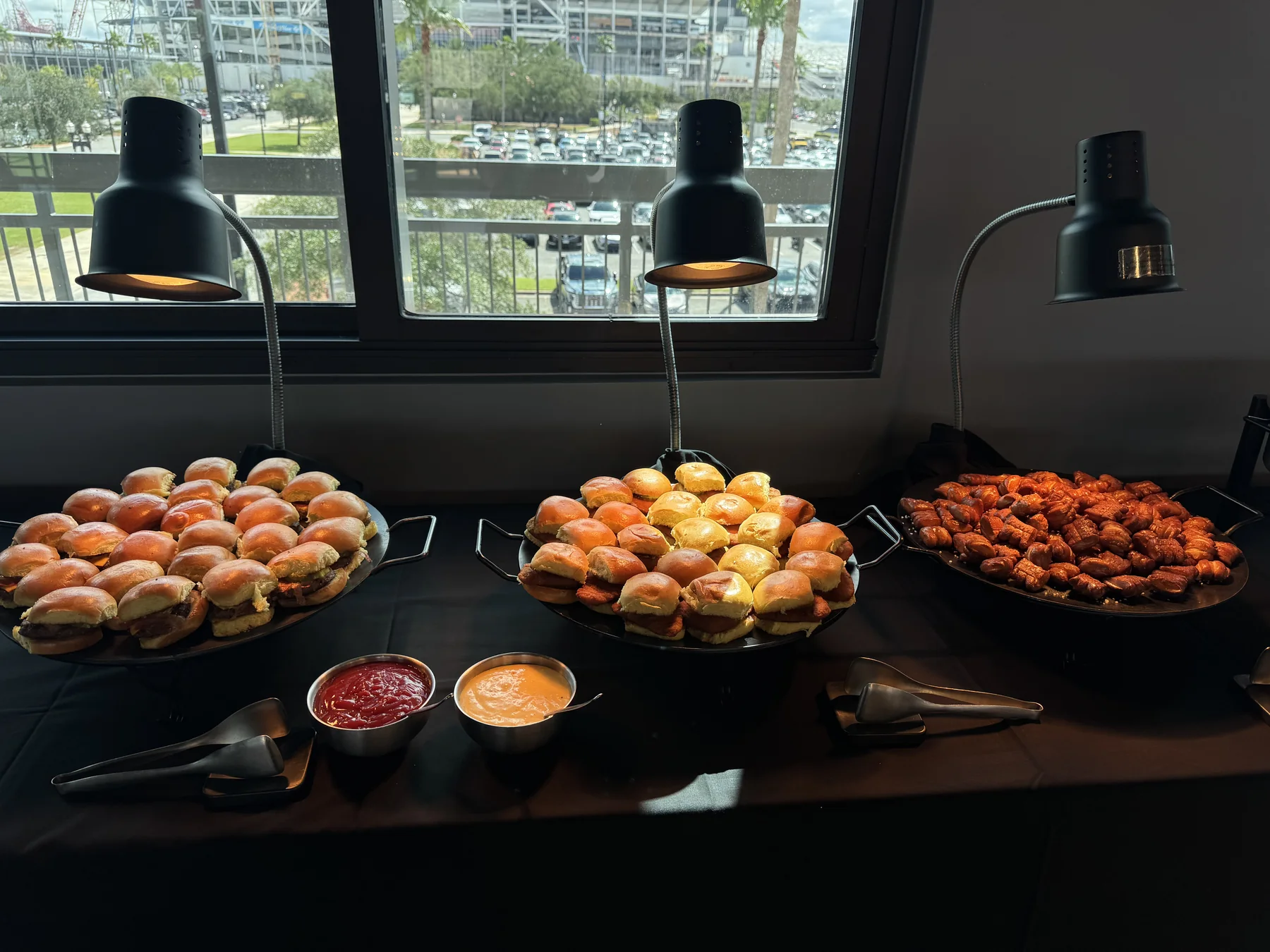 Trays of assorted sliders and wings with dipping sauces